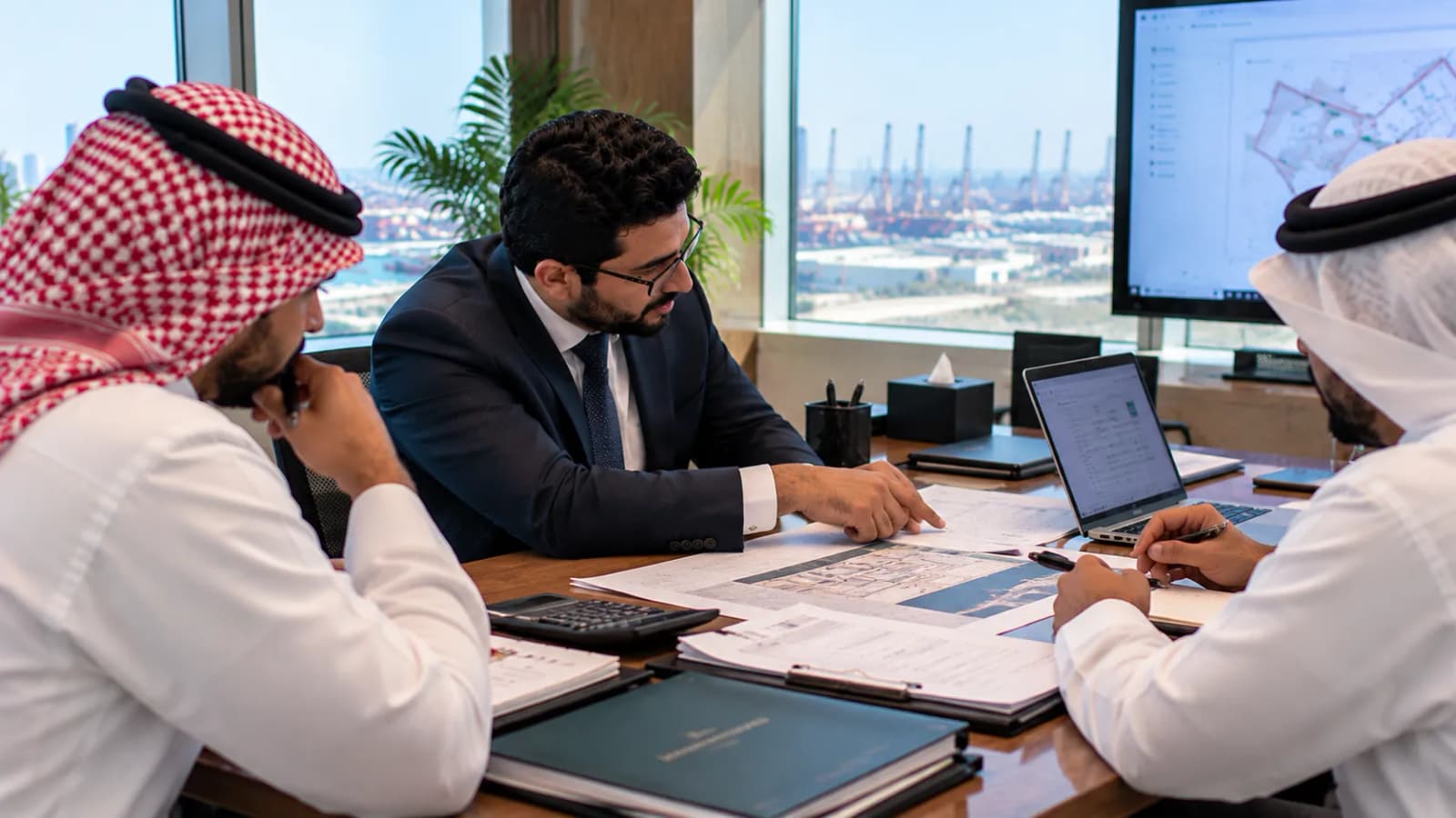 A consultant talking a government application file through with two clients at a meeting table